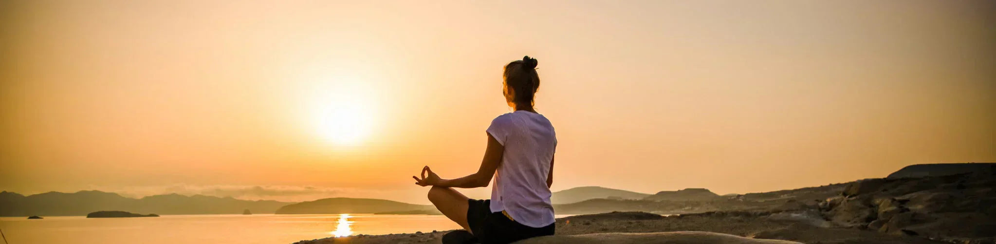 Person meditating at sunrise, representing the benefits of balanced bio frequencies for health and well-being.