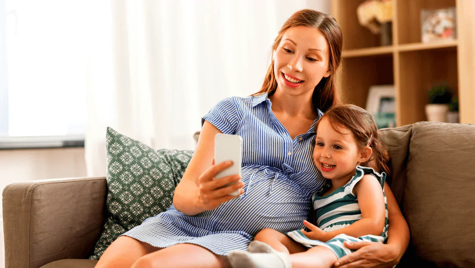 Expecting mother and young daughter enjoying screen time, symbolizing concerns about Prenatal EMF exposure.