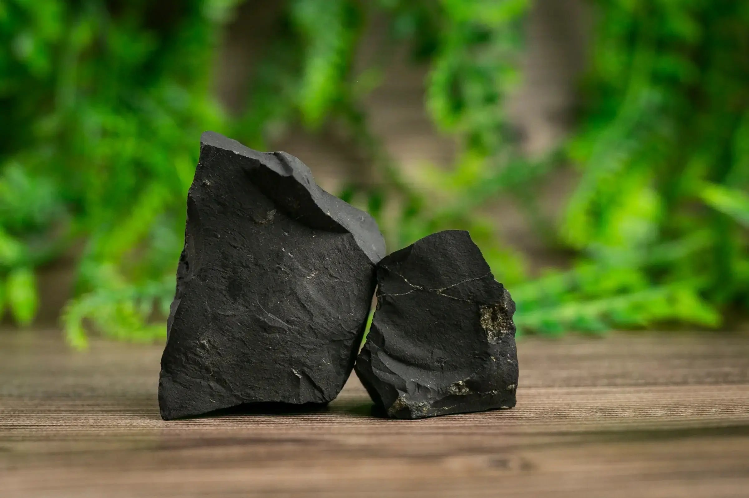 Shungite EMF protection benefits illustrated with natural black shungite stones on a wooden surface.