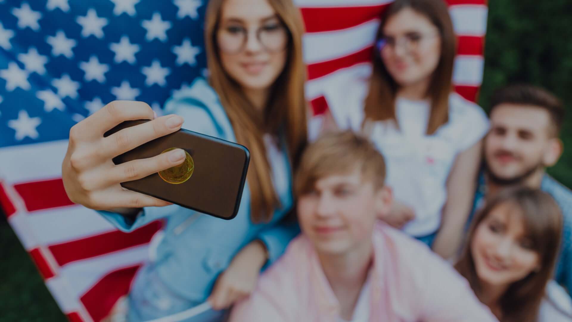 Group of friends taking a selfie in front of an American flag, discussing 5G health risks.