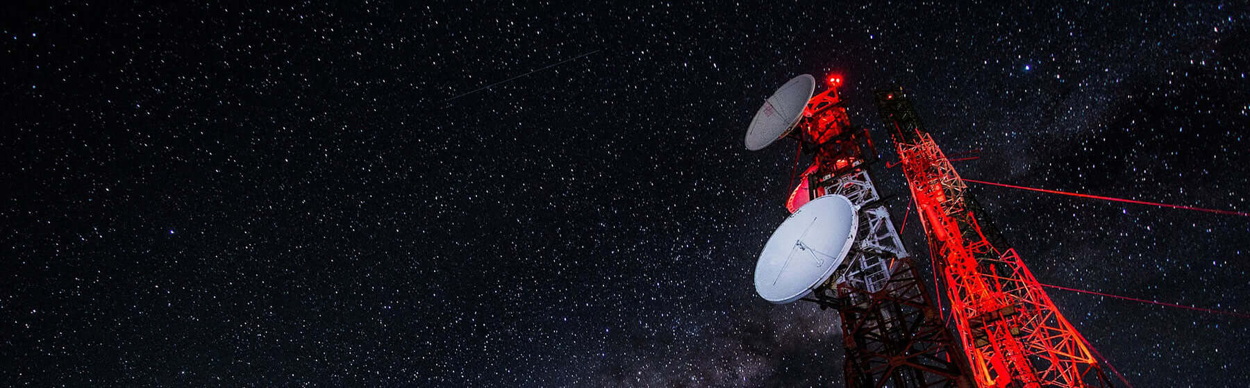 The 5G Wireless Network is expanding across the planet with a telecommunications tower under a starry night.