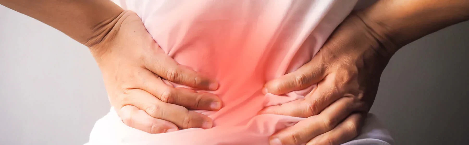 Person holding lower back, illustrating discomfort related to inflammation and oxidative stress in the body.