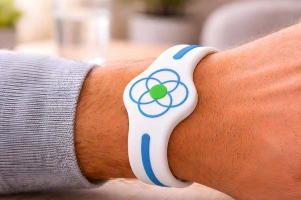 A Body Align Ultimate Wellness Band on a person's wrist with a blurred outdoor background.